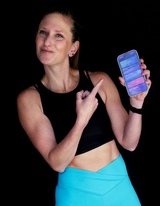 Kindal smirking and pointing to her phone with a daily fitness to-do list on it.